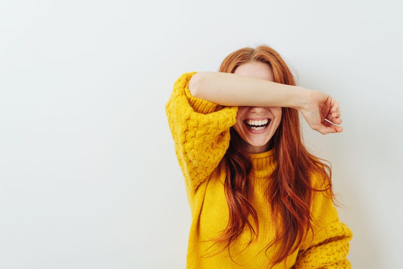 Smiling woman covering her eyes with her arm while waiting for a surprise 