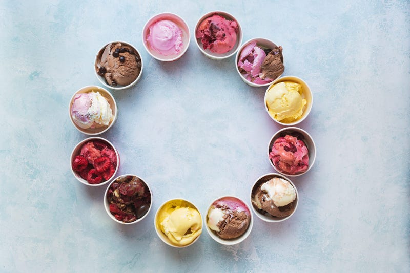 Different cups of ice cream flavors set in circle shape on rustic background