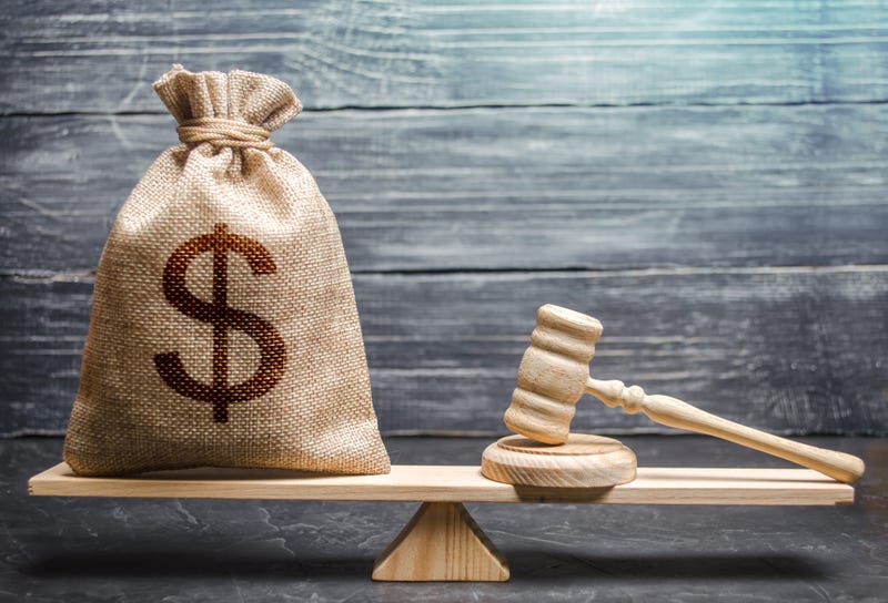 Bag of money with a dollar sign and a judge's hammer on the scales. 