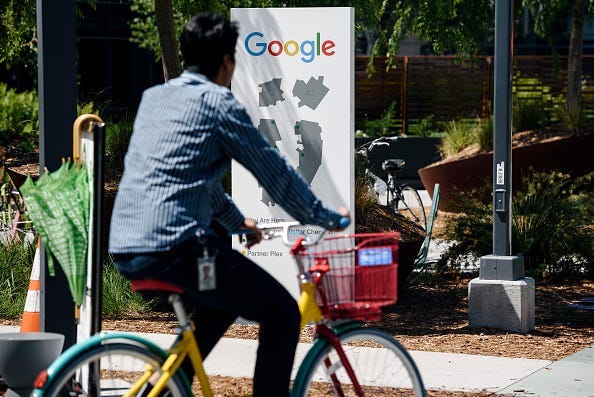 : People ride bikes past signage on the Google campus as Google workers inside hold a sit-in to protest sexual harassment at the company, on May 1, 2019 in Mountain View, California.