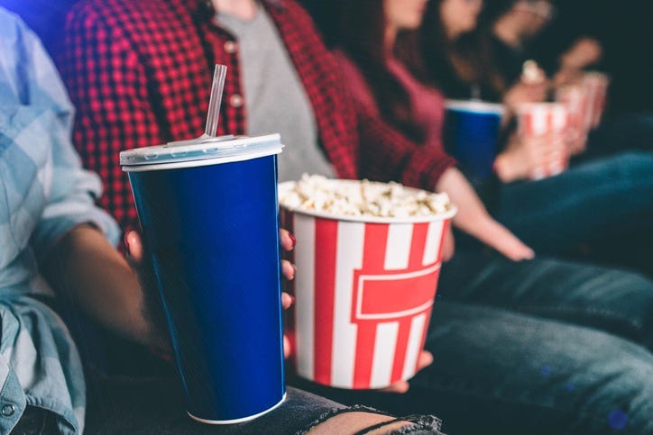 People holding popcorn and drinks in a movie theater. 