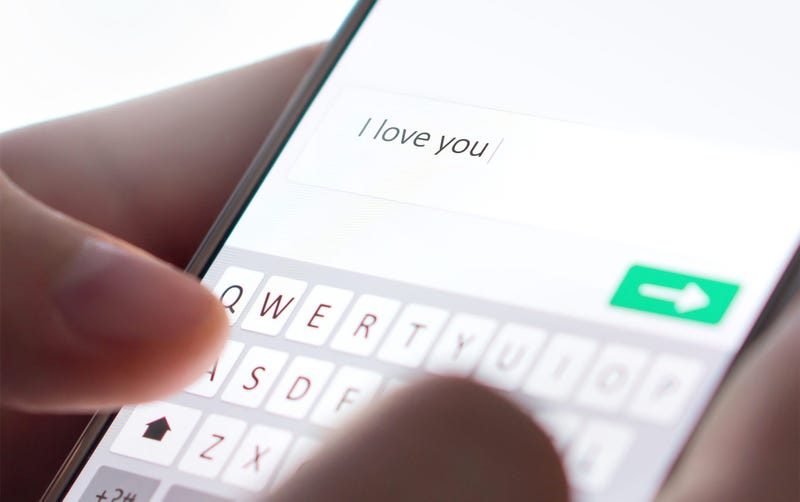 Sending I love you text message with mobile phone. Online dating, texting or catfishing concept. Romance fraud, scam or deceit with smartphone. Man writing comment. Fake profile. Internet safety