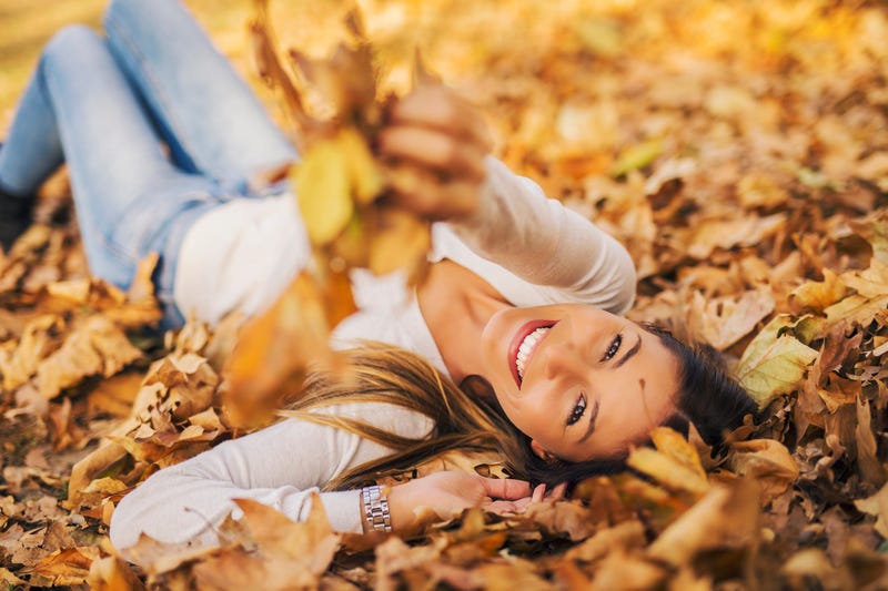 Woman laying down on the pile of leafs and playing