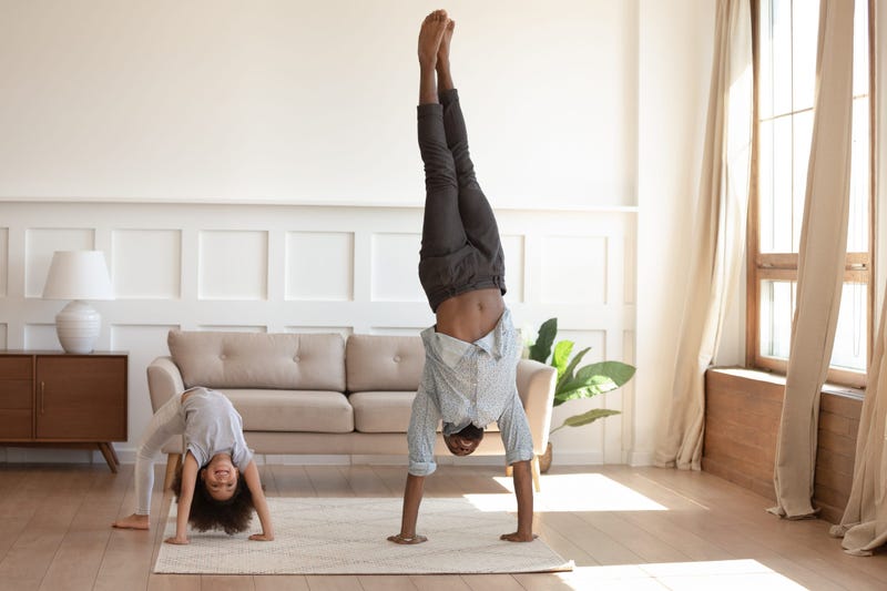 Happy african american girl doing bridge exercise, strong father staying on hands. Smiling black family doing morning exercises together in living room at home. Daily healthy habit concept.