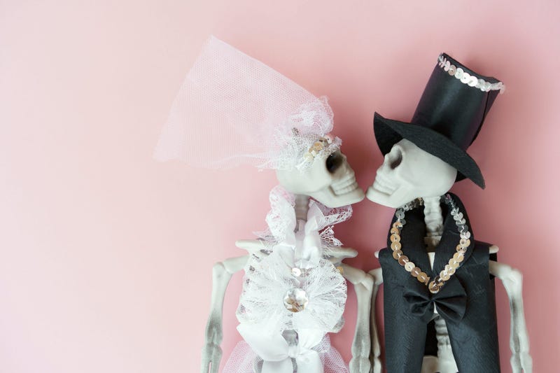 The skeletons in the bride groom wedding dress on the pale pink background. Creative stranger mock up trending Halloween party. 