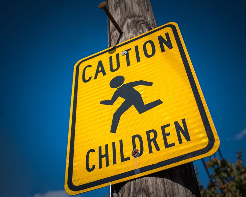 A yellow and black sign warning drivers to be cautious around children