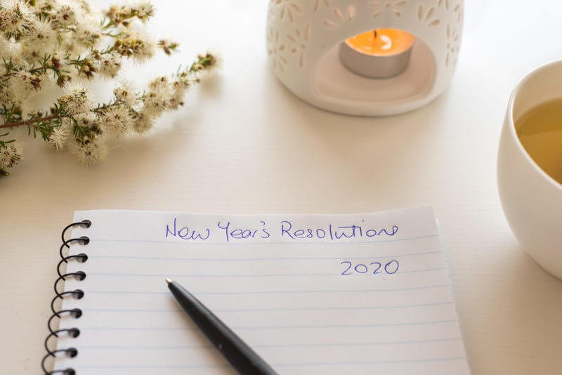 Notebook and pen with handwritten New Year's resolutions header.