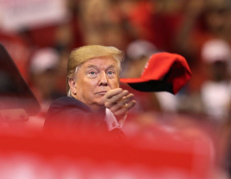 U.S. President Donald Trump tosses a hat into the crowd as he arrives to speak during a homecoming campaign rally at the BB&T Center on November 26, 2019 in Sunrise, Florida.