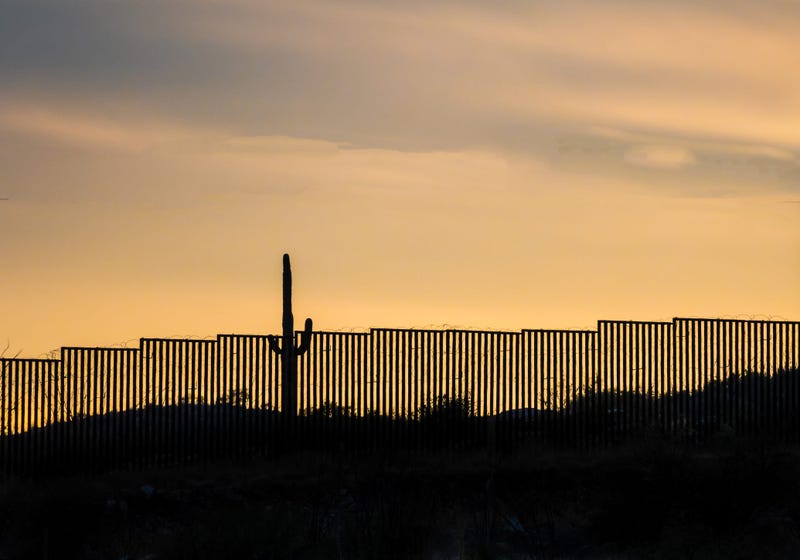 US -Mexico border wall at sunset with iconic saguaro cactus - stock photo