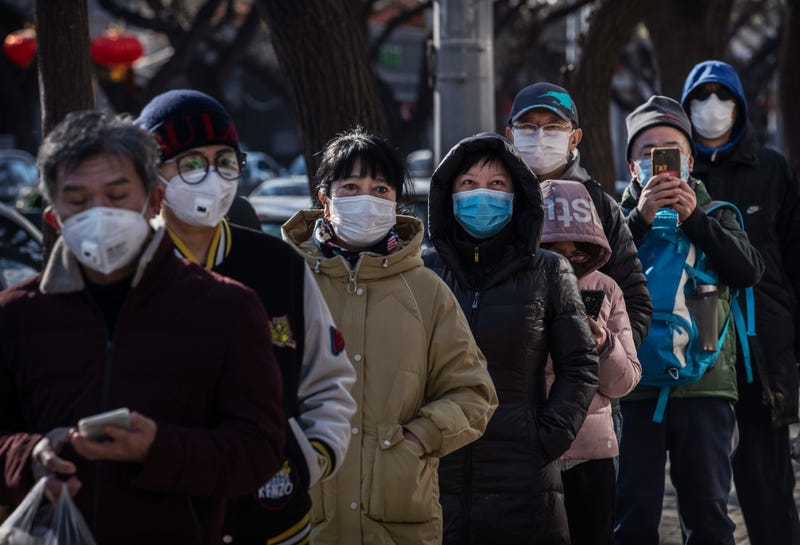  Chinese customers wear protective masks as they line up single file to buy dumplings at a popular local shop on February 16, 2020 in Beijing, China
