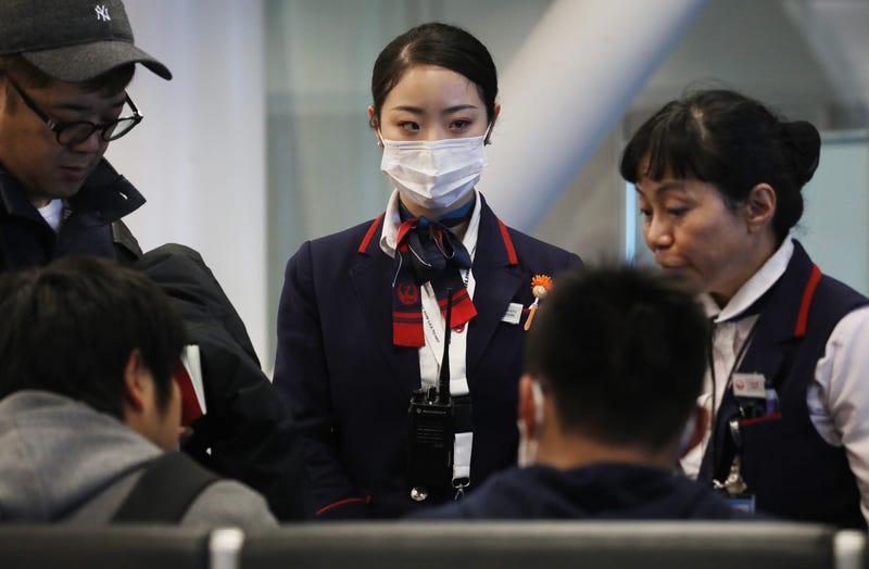 A Japan Airlines worker (C) wears a face mask while working inside a terminal at Los Angeles International Airport on Jan. 23, 2020.