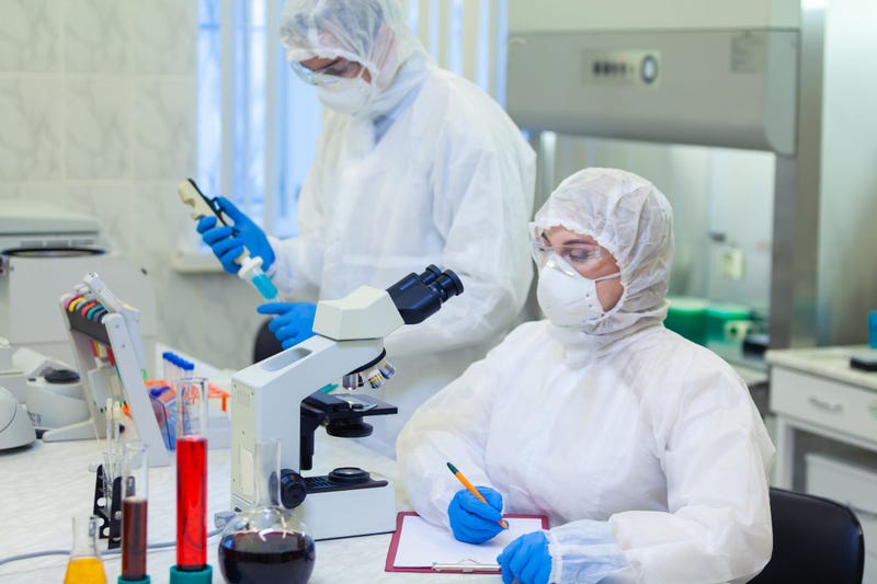 Scientists in protective suits in a science laboratory study a dangerous virus to eliminate the epidemic - stock photo