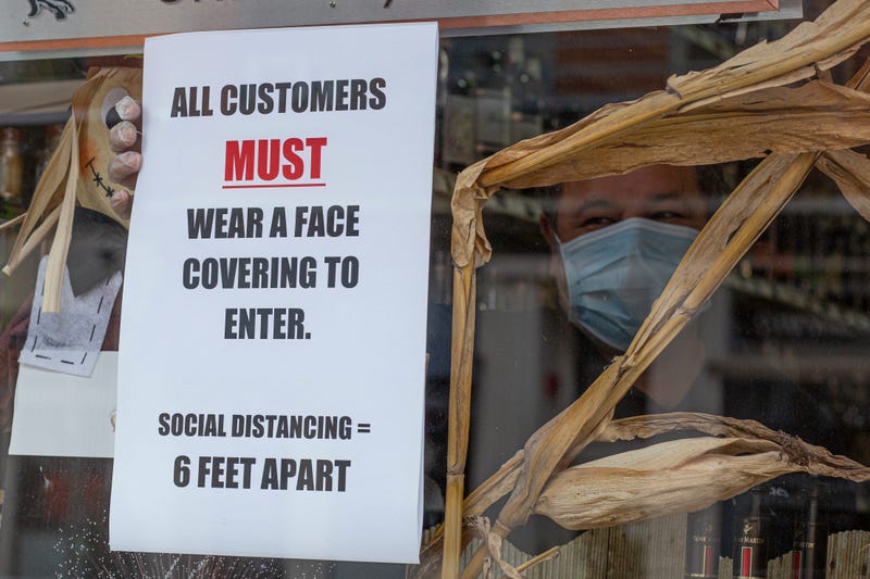 A worker places a placard on the window of a liquor store while wearing a face mask on April 10, 2020 in Jersey City, New Jersey.