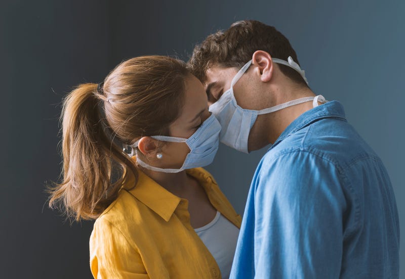 Young couple wearing protective face masks and kissing each other, virus spread prevention