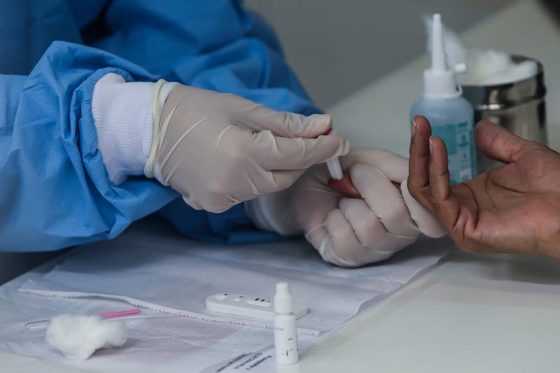 A health worker wearing a protective medical equipment extracts a blood sample from a patient's finger to make an antibody test for patients suspected of being infected with for the coronavirus (COVID-19)