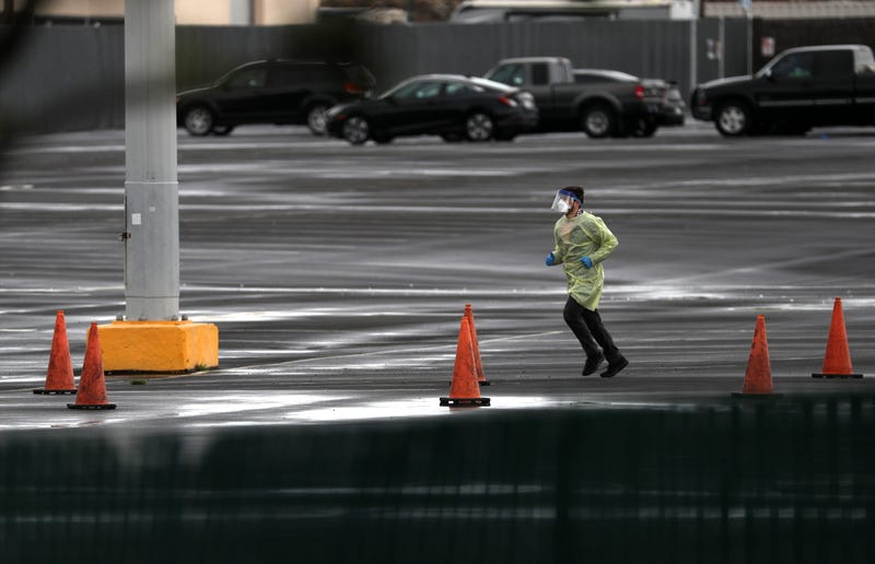 SAN MATEO, CALIFORNIA - MARCH 16: A medical worker runs across the parking lot during a coronavirus drive-thru test clinic at the San Mateo County Event Center on March 16, 2020 in San Mateo, California.
