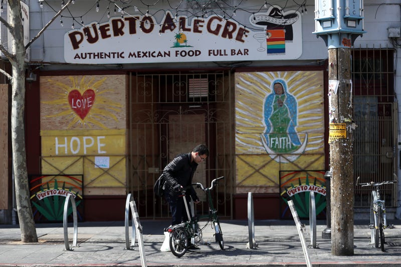 cyclist parks his bicycle in front of a business that has the windows covered with plywood on Valencia Street on March 20, 2020 in San Francisco