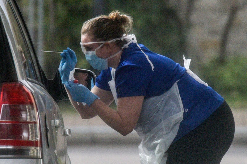 A nurse is seen swabbing the occupants of a car at a drive through COVID-19 testing station