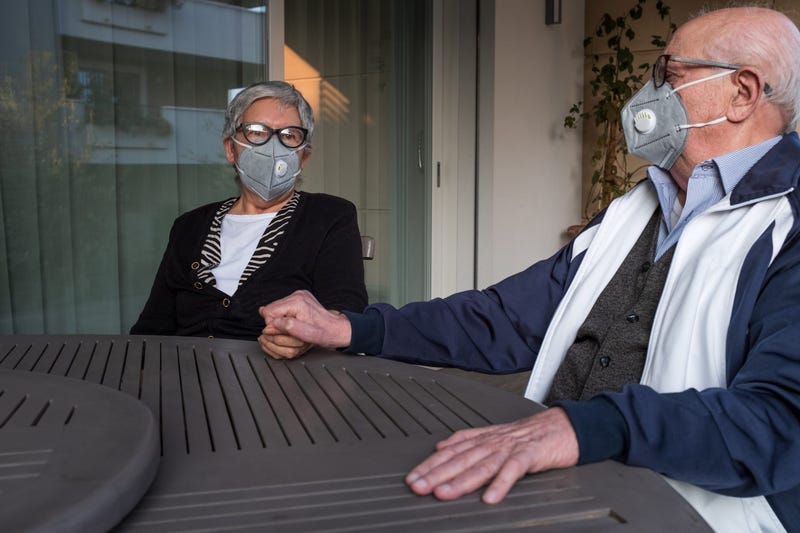 An elderly couple wearing a protective mask and holding hands