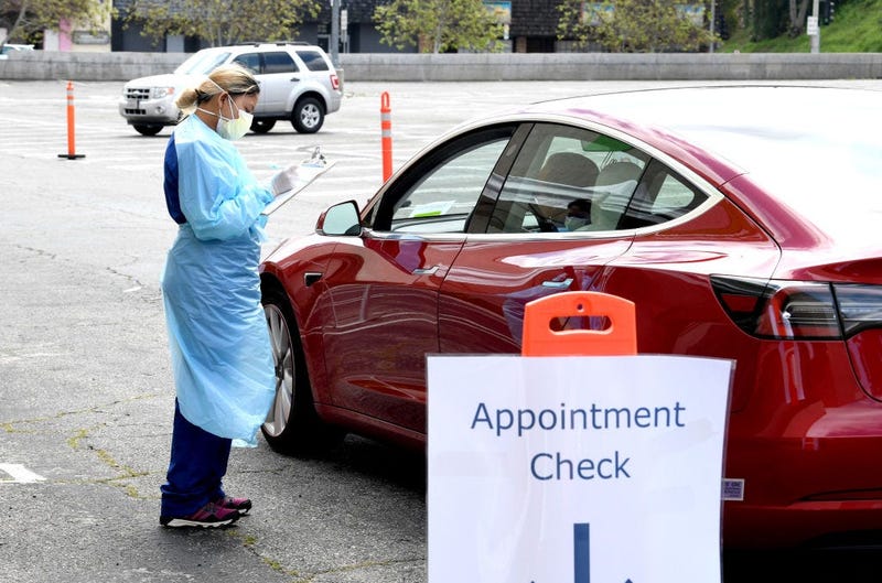 LOS ANGELES, CA - APRIL 13: A worker wearing personal protective equipment gathers the tests administered from a car as Mend Urgent Care hosts a drive-thru testing for the COVID-19 virus