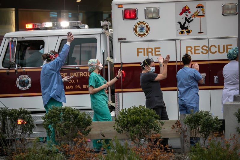 Hospital workers cheer as first responders pass by the Westchester Medical Center in a caravan of sirens and lights on April 14, 2020 in Valhalla, New York.