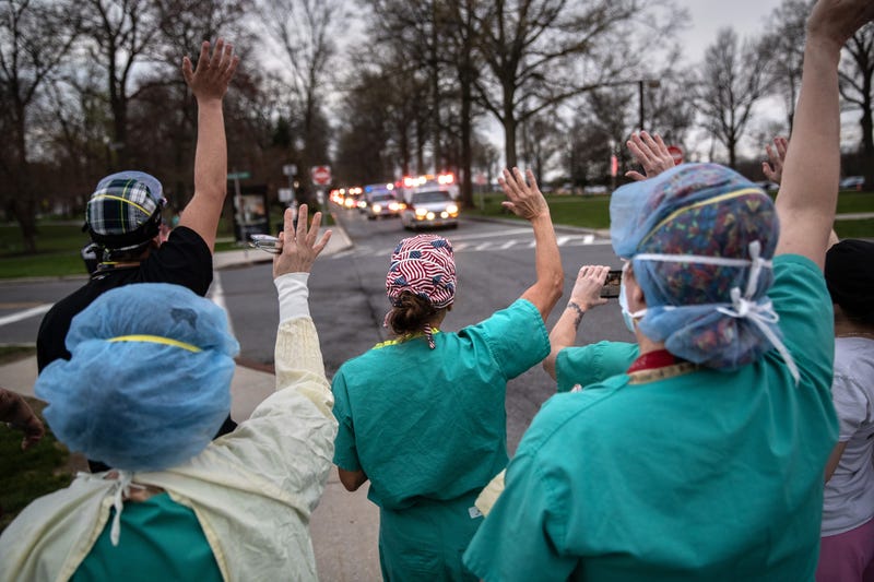 Hospital workers wave and cheer outside the Westchester Medical Center as first responders pass by in a caravan of sirens and lights on April 14, 2020 in Valhalla, New York.
