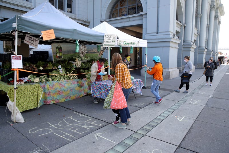 People practice social distancing as they wait in line to purchase produce from a vendor during the Ferry Plaza Farmers Market on April 21, 2020 in San Francisco, California