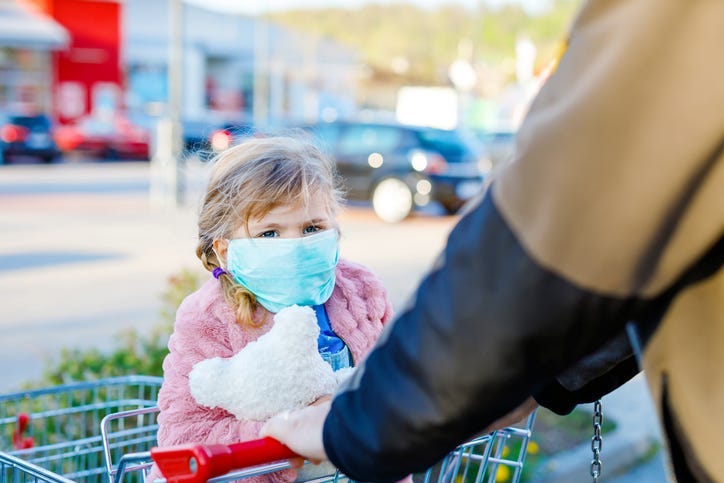 Little Girl Wearing Mask in Shopping Cart - Getty Images