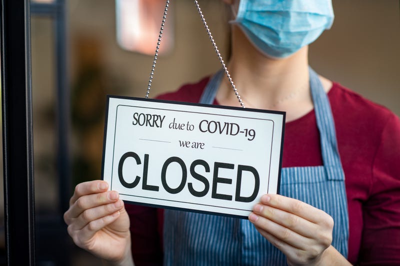 Businesswoman closing her business activity due to covid-19 lockdown. Owner with surgical mask close the doors of her store due to quarantine coronavirus damage.