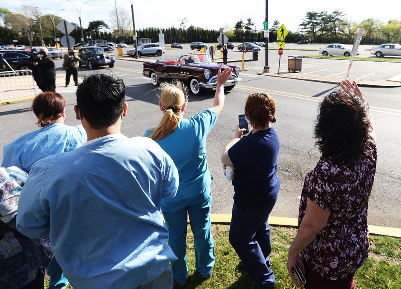 Healthcare workers wave as a parade of classic cars makes its way by Nassau University Medical Center in a salute to workers on the front lines of the COVID-19 pandemic on May 04, 2020 in East Meadow, New York.