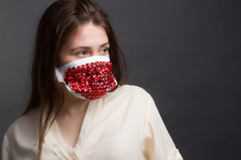 Studio portrait of Woman in protective mask with red rhinestones on a grey background