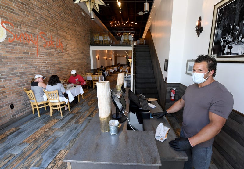 Owner Nicholas Sord wears a mask and gloves while patrons dine at his Sunny Side Up restaurant in Boca Park Fashion Village as some businesses that were closed seven weeks ago to fight the spread of the coronavirus are allowed to reopen on May 9, 2020