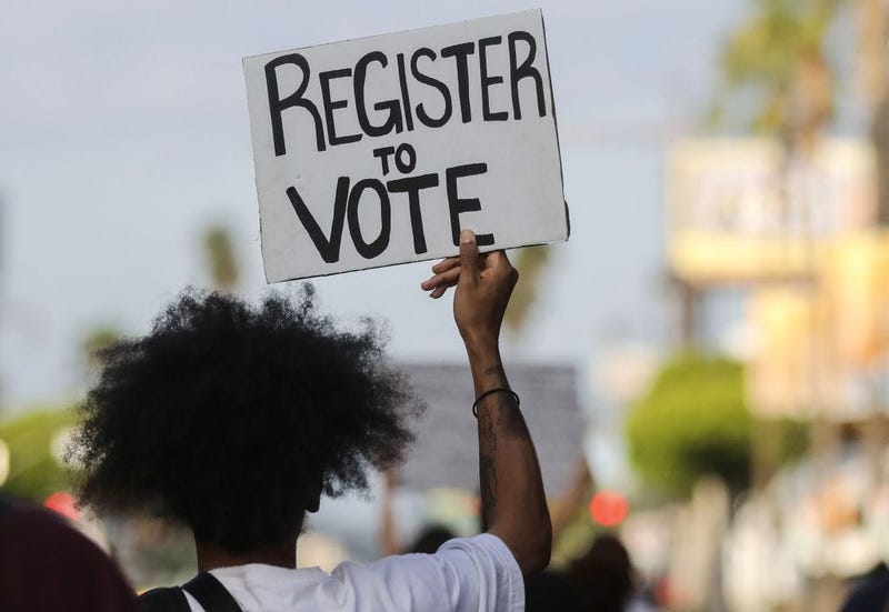 A protester carries a 'Register to Vote' sign during a peaceful demonstration against racism and police brutality on June 06, 2020 in Los Angeles, California