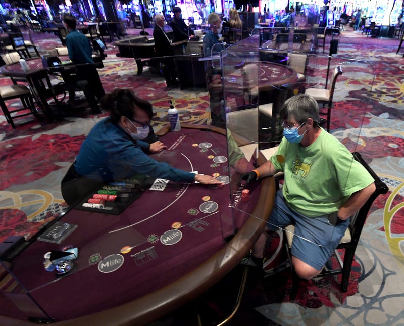 Nila Davis (L) deals cards to Becky Lewis of Texas at a blackjack table with plexiglass safety shield dividers at Excalibur Hotel & Casino after the Las Vegas Strip