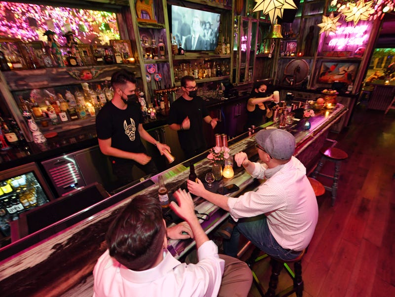 Barback Jaime Torres, bar manager Chance Bennett and bartender Brandi Sterner work behind the bar as Pete Cangelosi (L) and his friend Mike Silva, both of Louisiana, become the first patrons to sit at the bartop after it opened