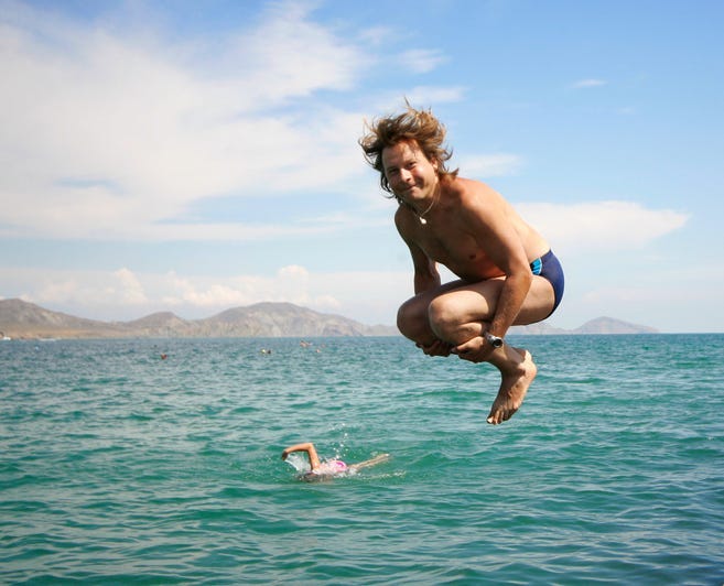 Man jumping into ocean wearing blue Speedo