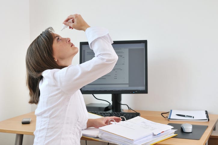 A person using eye drops.