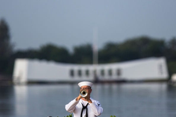 A U.S. Navy musician plays echo 'Taps' in front of the U.S.S. Arizona Memorial during the 71st Annual Memorial Ceremony commemorating the WWII Attack On Pearl Harbor