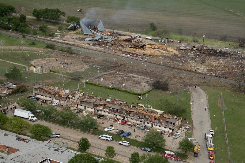 File Photo: Search and rescue workers comb through what remains of a 50-unit apartment building (foreground) the day after an explosion at the West Fertilizer Company (background) destroyed the building April 18, 2013 in West, Texas. According to West May