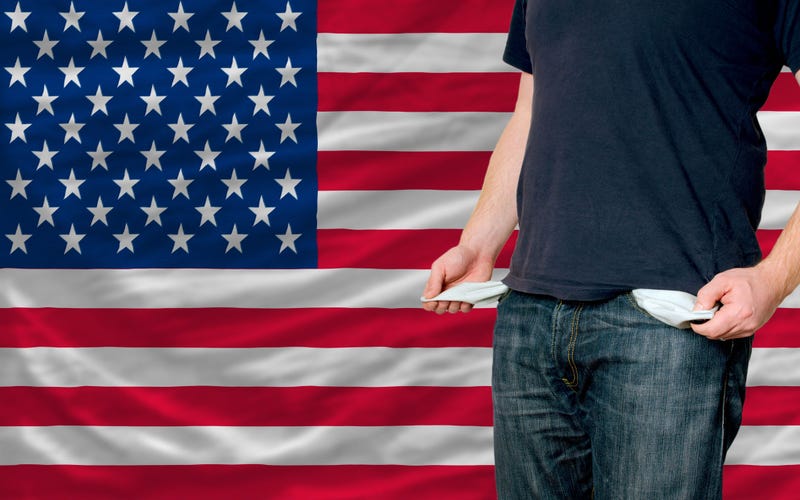 Man shows empty pockets while standing in front of American flag