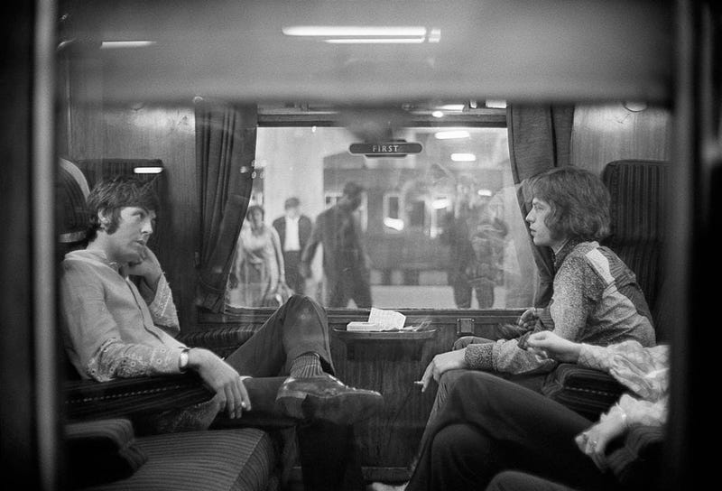  Paul McCartney of the Beatles and Mick Jagger of the Rolling Stones sit opposite each other on a train at Euston Station, waiting for departure to Bangor. 