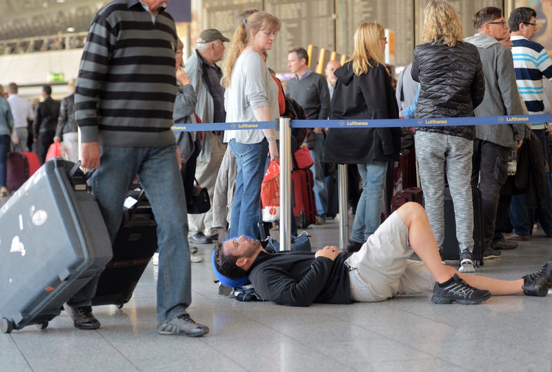 : A passenger takes a nap as other passengers wait in line for Lufthansa flights on October 20, 2014 in Frankfurt am Main, Germany