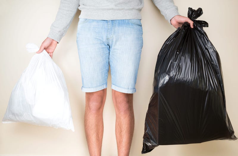 White garbage bag and black garbage back being carried out.
