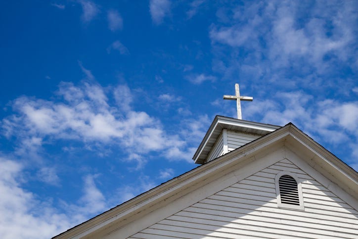 Church Steeple And Cross Set Against A Blue Sky