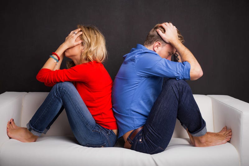 Couple with their backs turned to each other sitting on couch