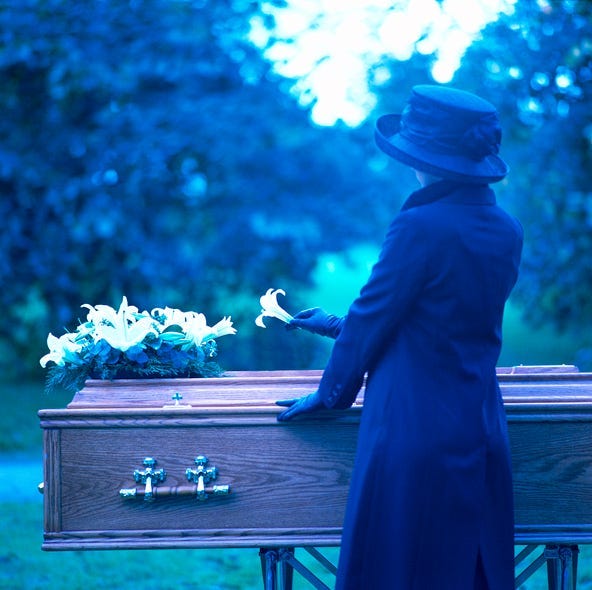 a woman placing a flower on a coffin