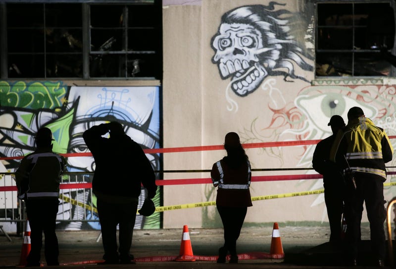 Workers and emergency responders look at a warehouse in which a fire claimed the lives of at least thirty-six people on December 5, 2016 in Oakland, California.