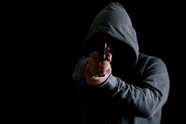 Man in green hoodie points gun