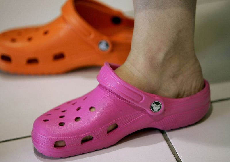 woman shops for Crocs to replace her old sandals in a shoe store