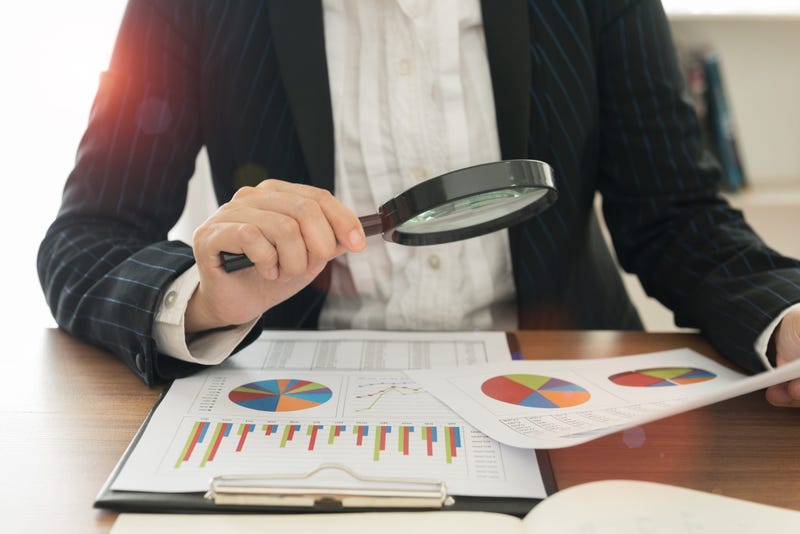 Auditor uses magnifying glass to look over financial papers